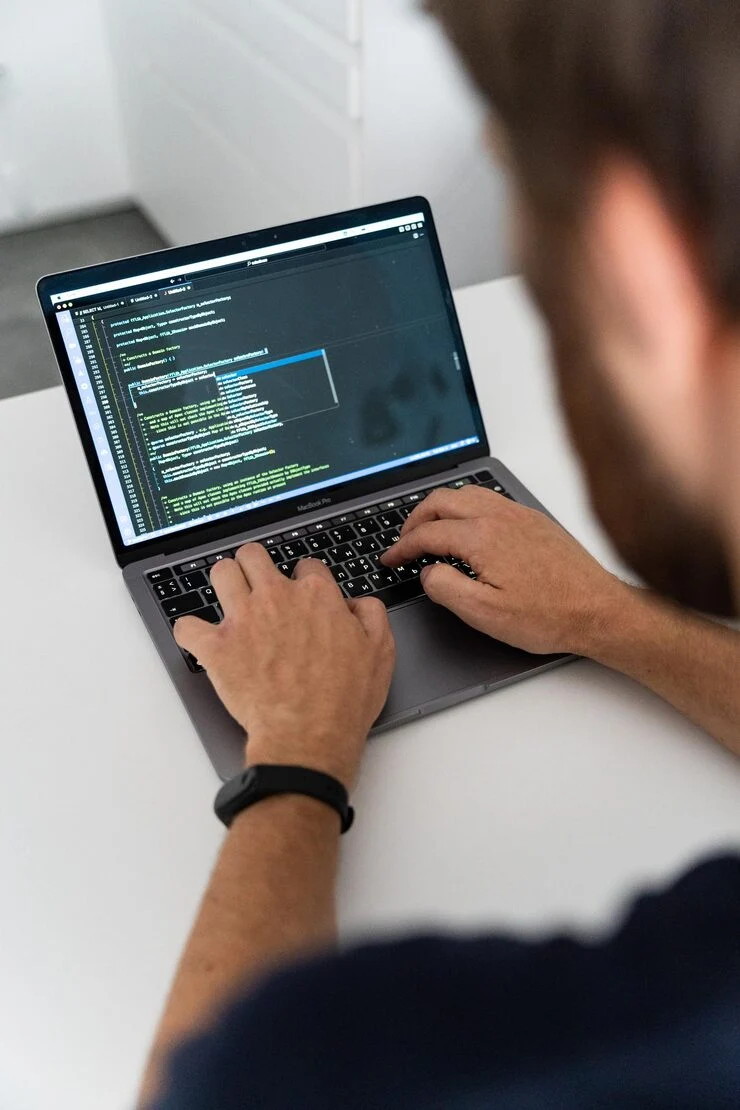MAN IS TYPING LAPTOP WITH SCREEN SHOWING WEB PAGE_1260911 15 | Cekome Développeur tapant du code sur un ordinateur portable MacBook Pro dans un environnement de travail épuré