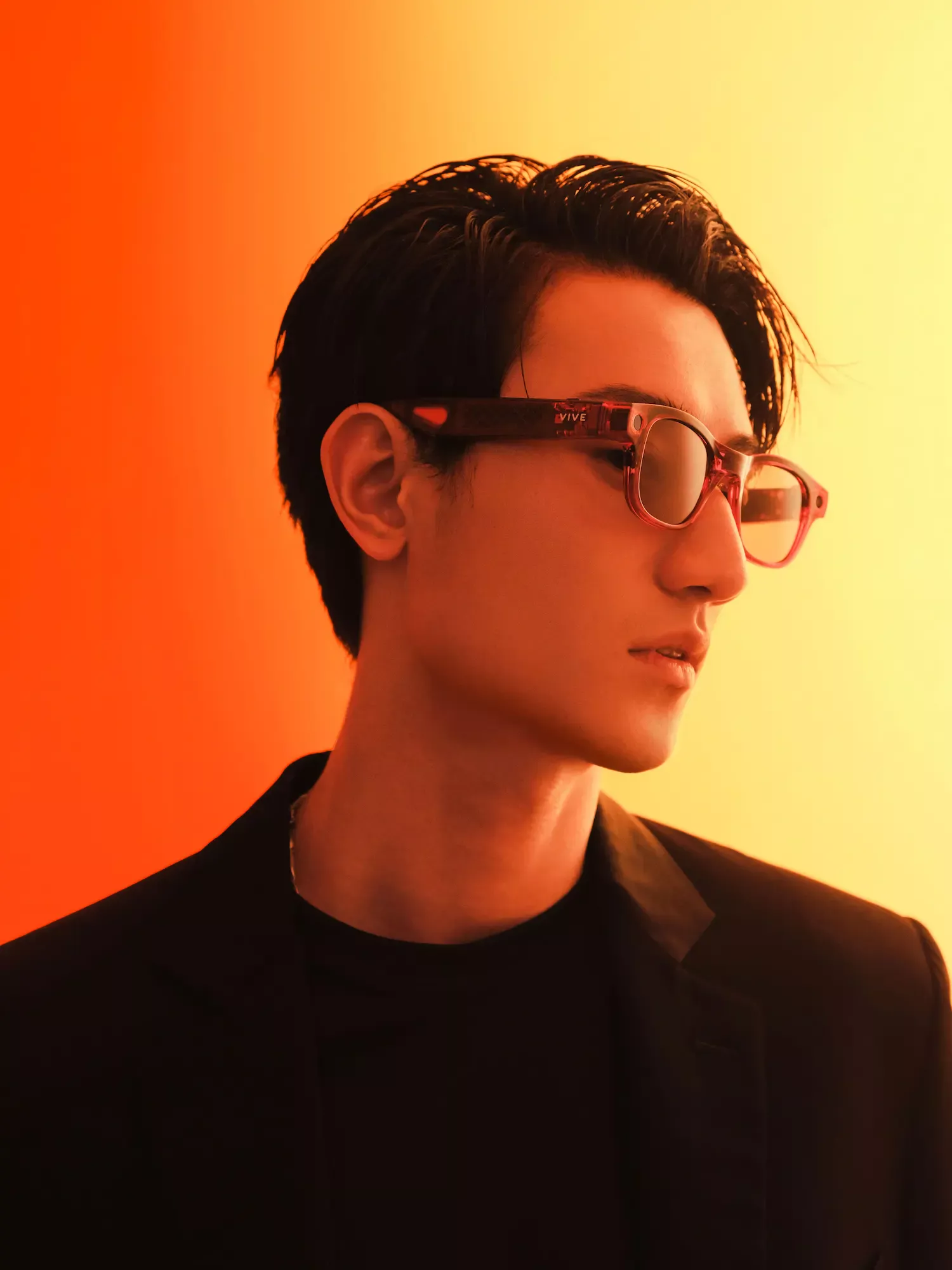 Homme portant des lunettes intelligentes VIVE EAGLE rouges avec un fond dégradé orange et jaune