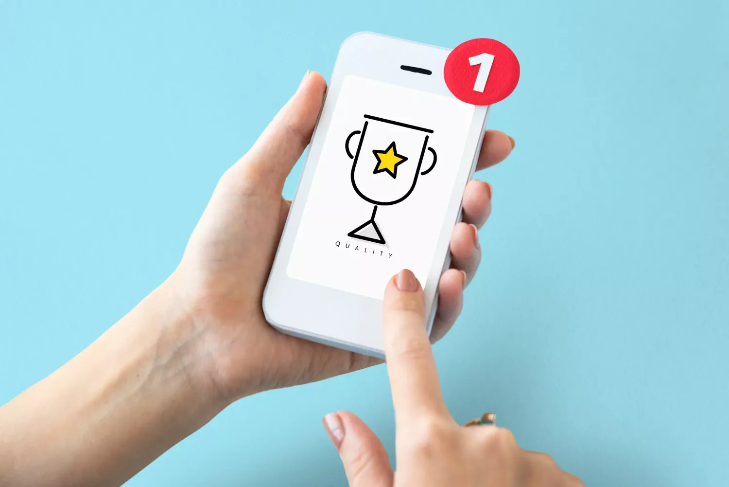 Main tenant un smartphone affichant un trophée avec une étoile et une notification de succès numérique, symbolisant la reconnaissance de qualité ou l’obtention d’une récompense digitale.
