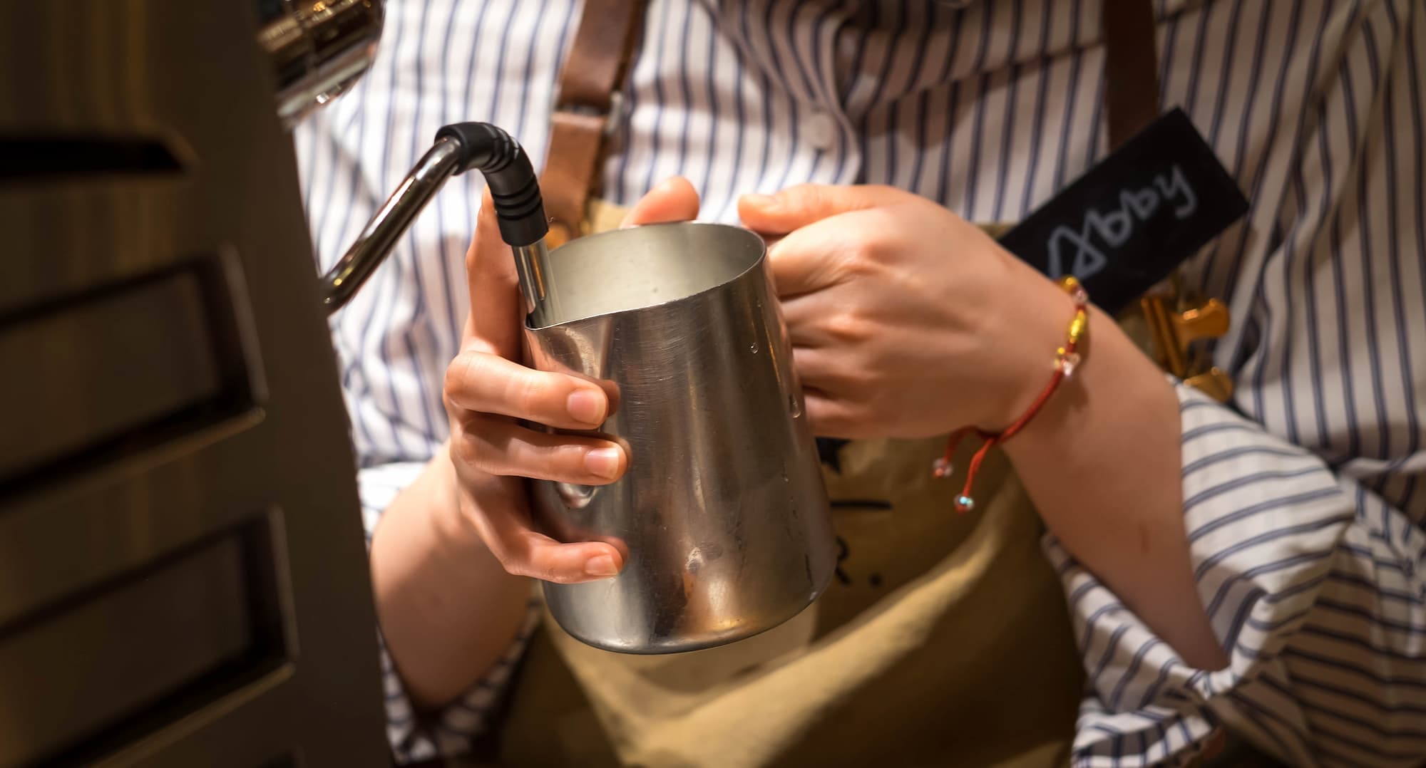 BARISTA FAISANT CHAUFFER DU LAIT DANS UN POT EN METAL A LAIDE DUNE BUSE VAPEUR | Cekome Barista faisant chauffer du lait dans un pot en métal à l’aide d’une buse vapeur
