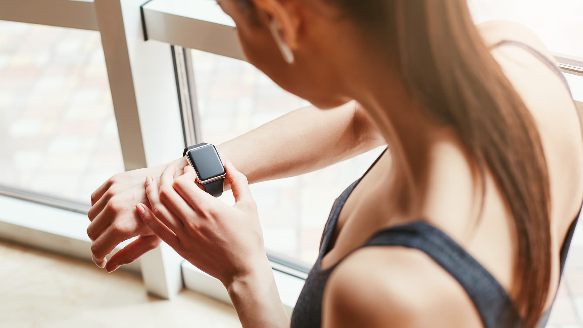 FEMME CONSULTANT SA MONTRE CONNECTEE APRES UNE SEANCE DE SPORT | Cekome Femme consultant sa montre connectée après une séance de sport.