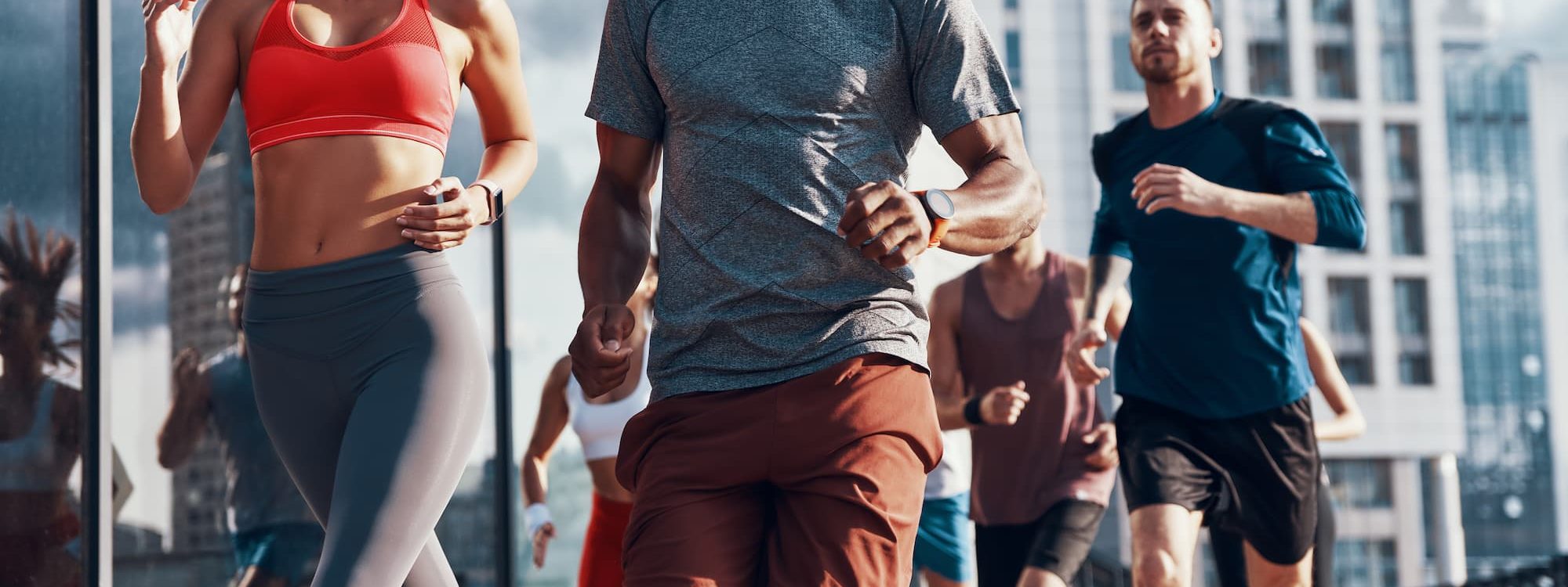 Groupe de coureurs faisant du jogging en ville pr&egrave;s d&rsquo;un immeuble moderne