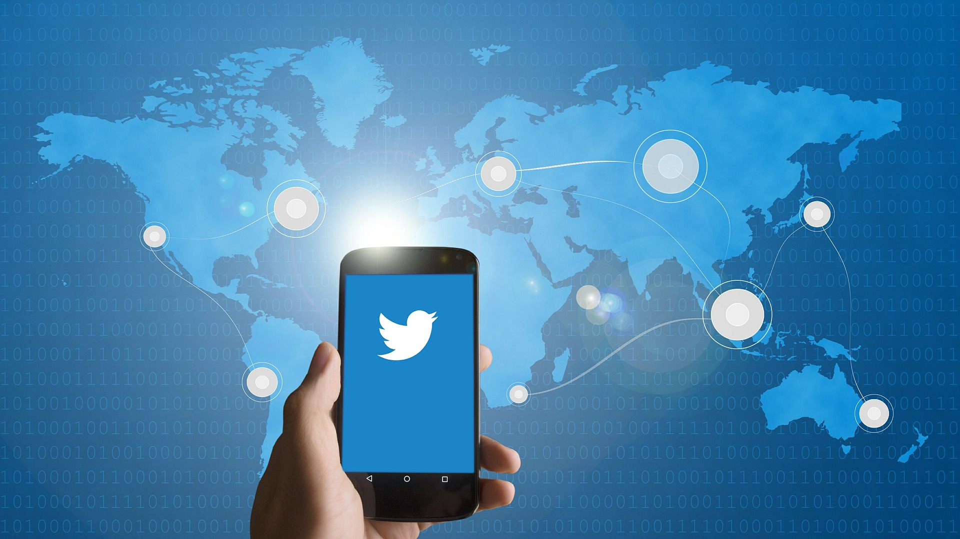 MAIN TENANT UN SMARTPHONE AVEC LE LOGO TWITTER DEVANT UNE CARTE DU MONDE CONNECTEE | Cekome Main tenant un smartphone avec le logo Twitter devant une carte du monde connectée