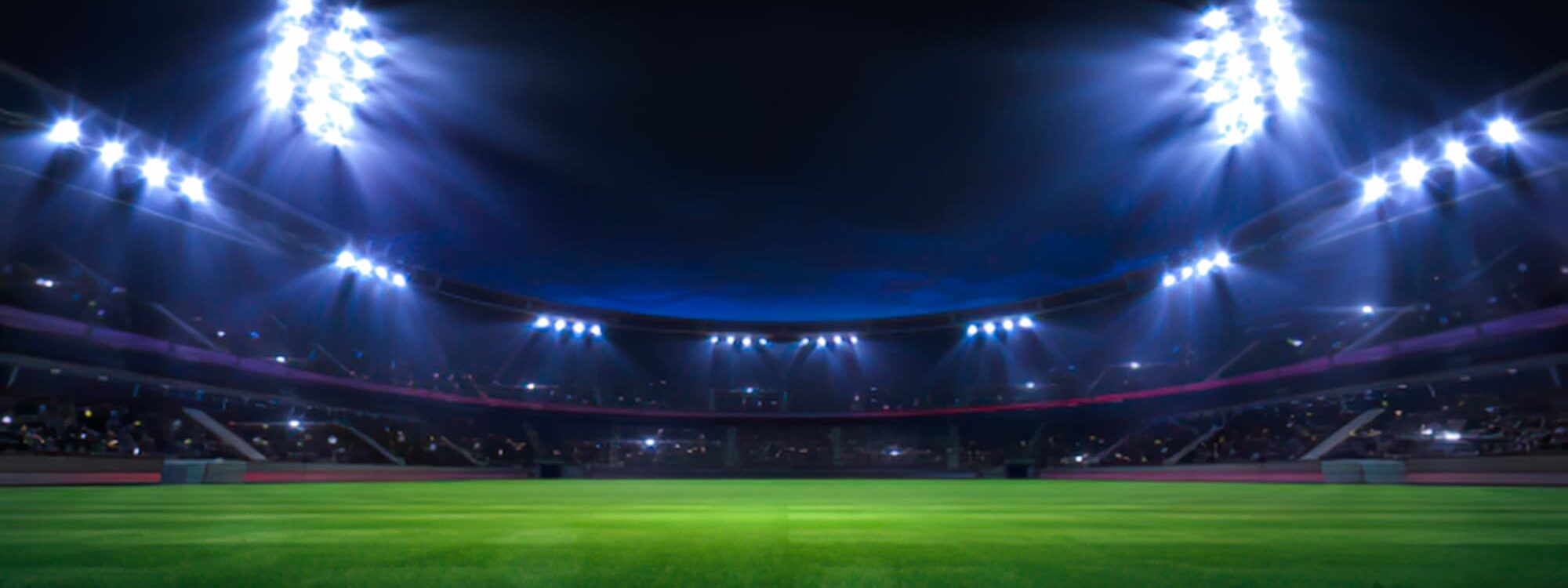 STADE DE FOOTBALL ECLAIRE LA NUIT AVEC GRADINS REMPLIS 2000X750 | Cekome Stade de football éclairé la nuit avec gradins remplis.