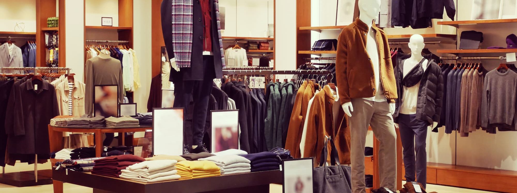 Vitrine de magasin de v&ecirc;tements avec mannequins habill&eacute;s et v&ecirc;tements pli&eacute;s sur des pr&eacute;sentoirs