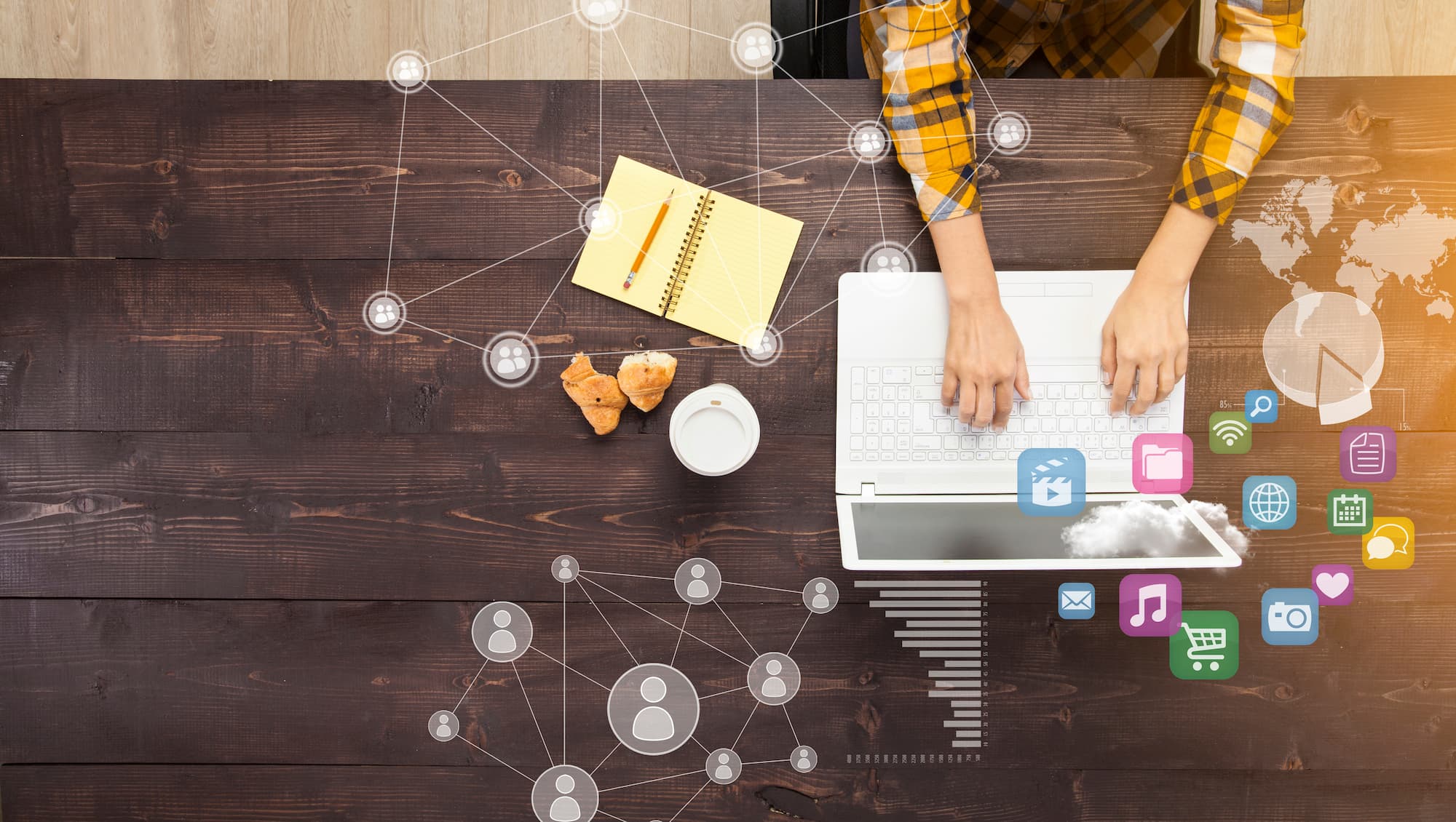 VUE DE DESSUS DUNE PERSONNE TRAVAILLANT SUR UN ORDINATEUR PORTABLE AVEC DES ICONES NUMERIQUES CARNET CROISSANTS ET CAFE SUR UNE TABLE EN BOIS | Cekome Vue de dessus d'une personne travaillant sur un ordinateur portable avec des icônes numériques, carnet, croissants et café sur une table en bois