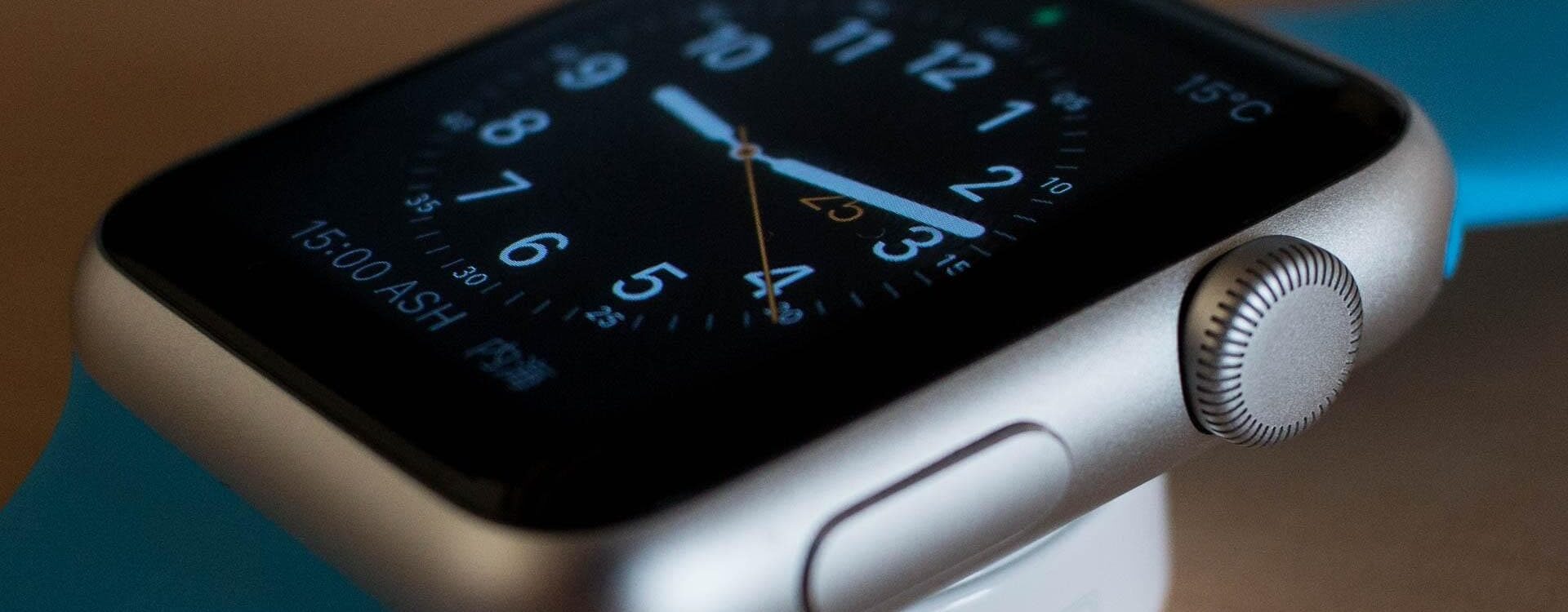 CLOCK 756487_1920 1920X750 | Cekome Gros plan d'une Apple Watch en charge, affichant un cadran analogique avec bracelet bleu