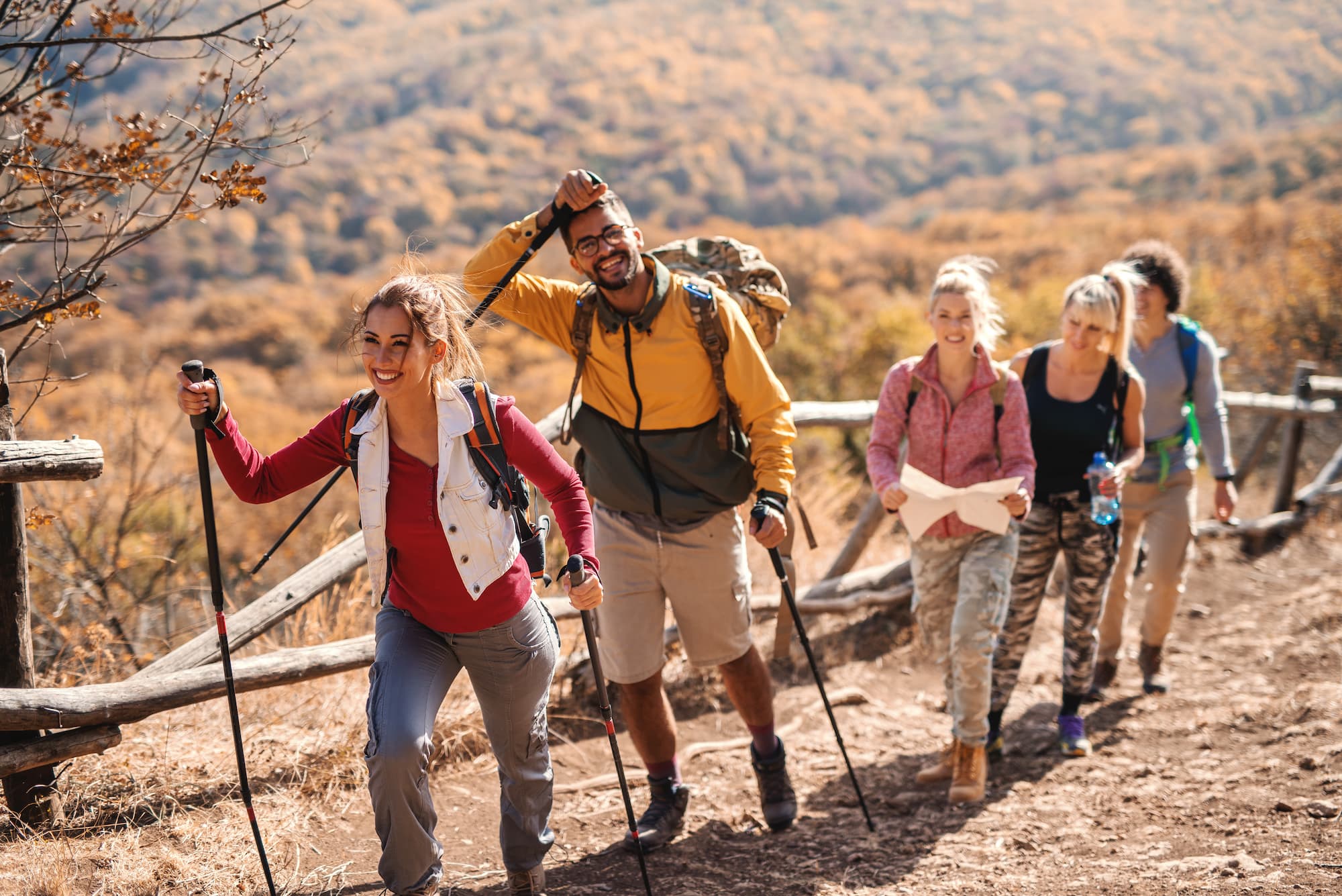 ADOBESTOCK_238443064 | Cekome Groupe d’amis souriants en pleine randonnée sur un sentier de montagne automnal.